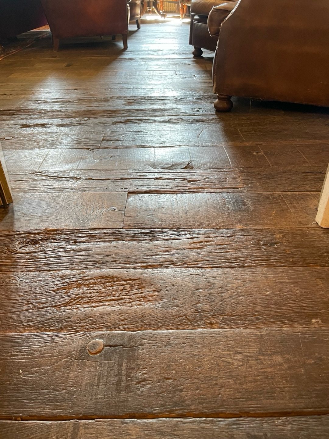 Weathered dark wood planks with deep textures and visible grain in a rustic room setting.