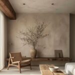 A textured beige limewash wall in a minimalist room with wooden furniture and dried branches.