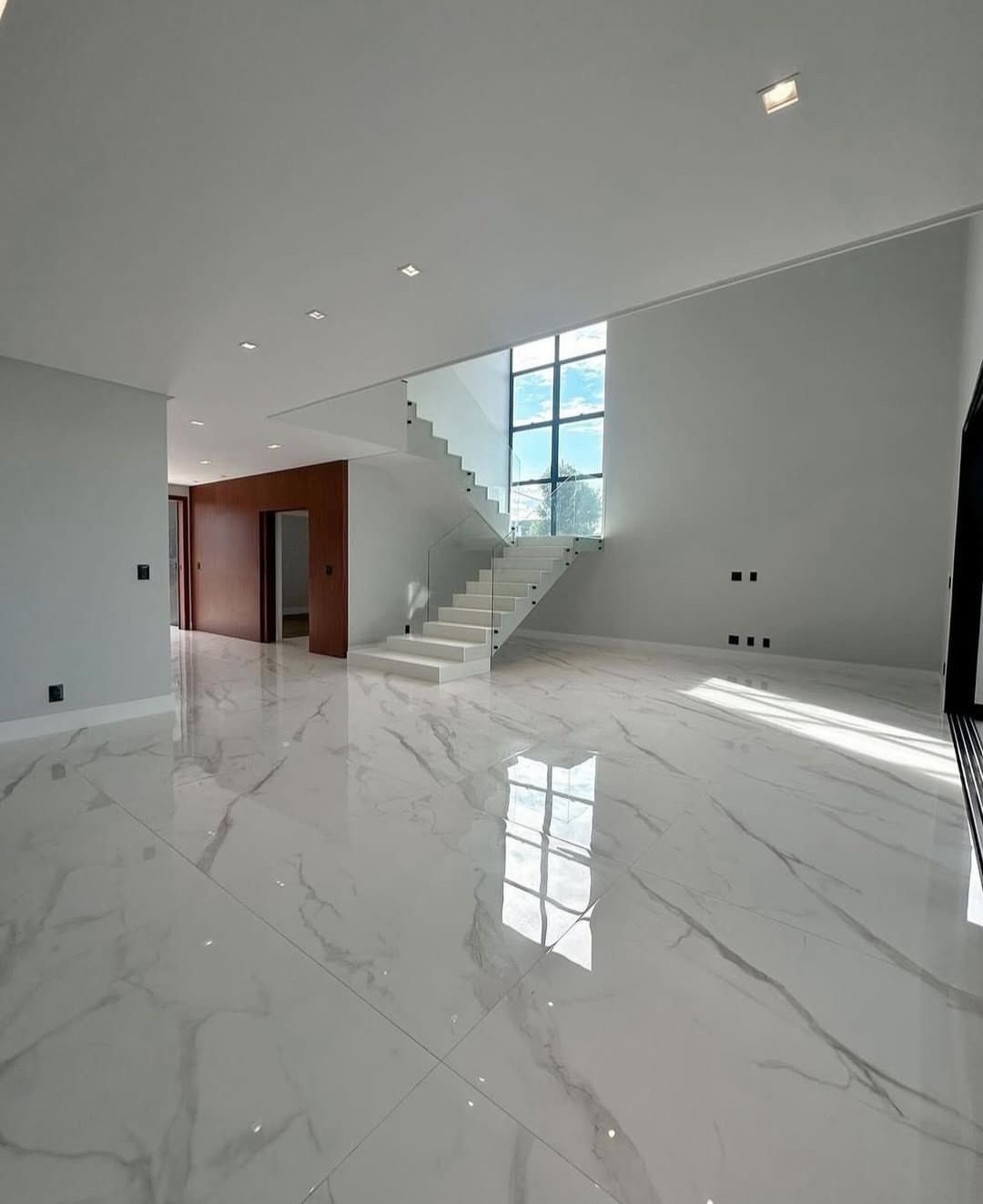 Polished white marble flooring with grey veins in a bright, modern minimalist room.
