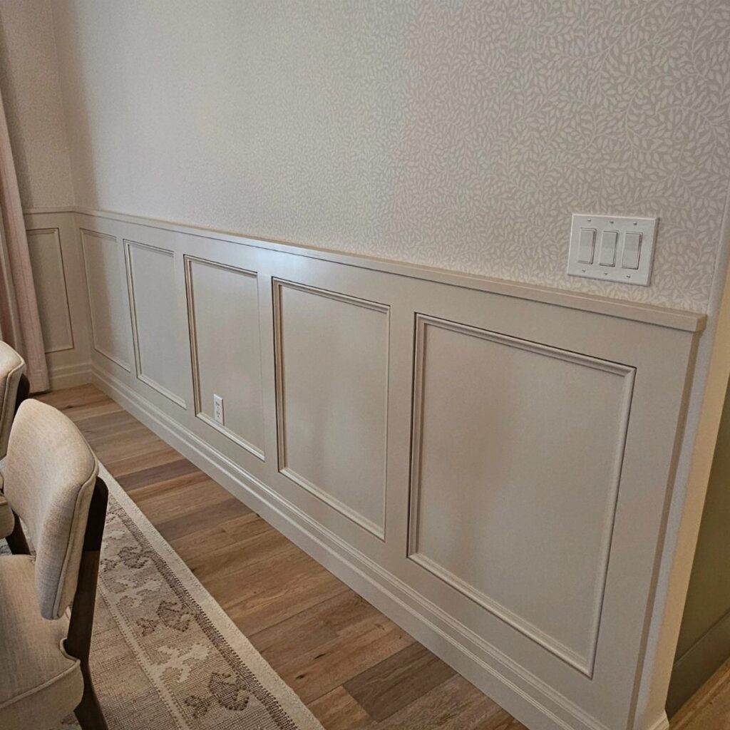 Decorative wainscoting with rectangular panel molding installed on a light-colored interior wall.