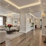 White wainscoting panels on walls in a modern living room with wooden floors and a chandelier.
