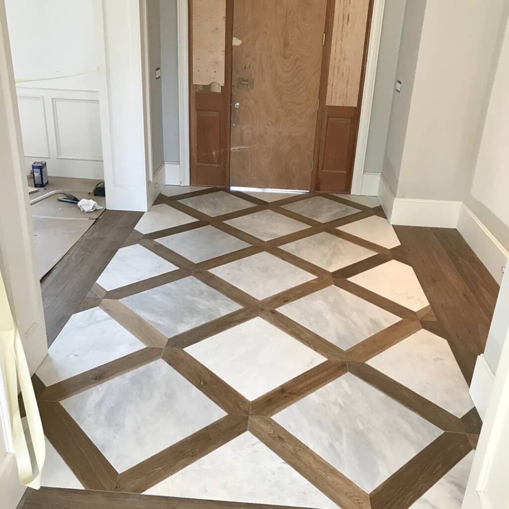 Geometric wood tile pattern with white marble squares and brown wood borders on a hallway floor.